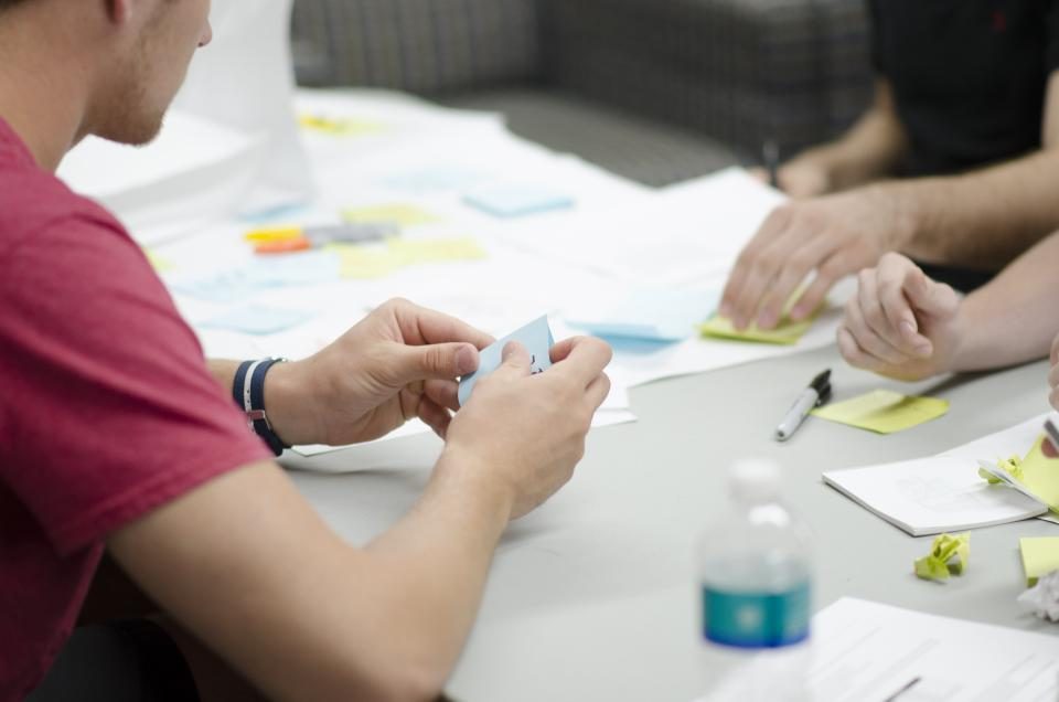 Team planning around a table with notes, charts and a laptop